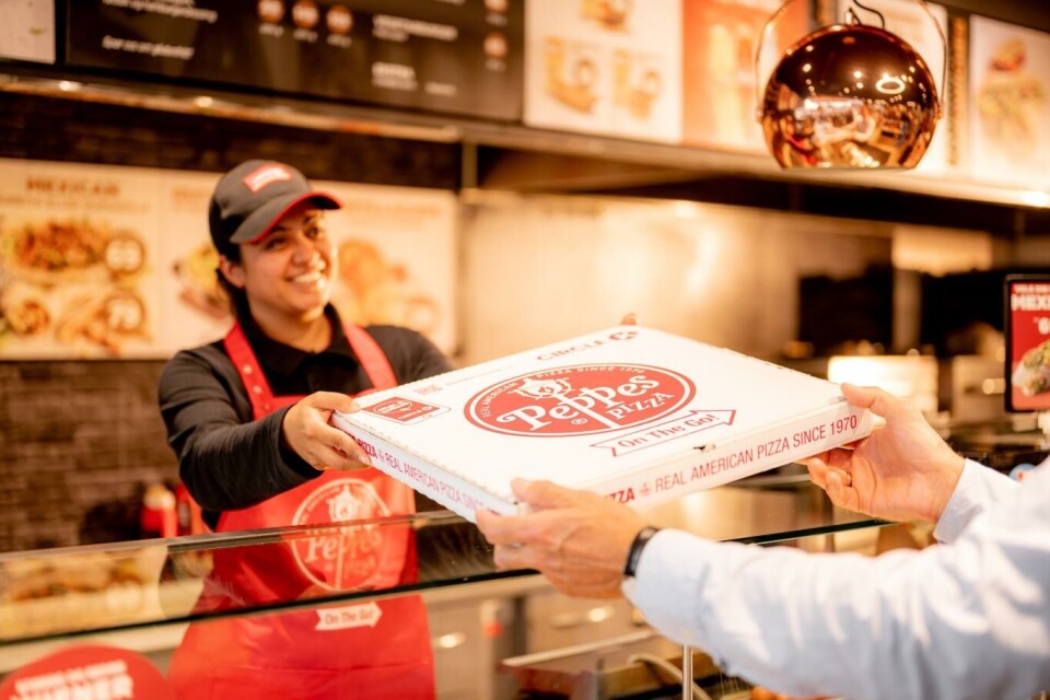 Aina Javed Akhtar, daglig leder på Circle K Kjeller, tilbyr når Peppes On-The-Go. Foto: Terje Borud